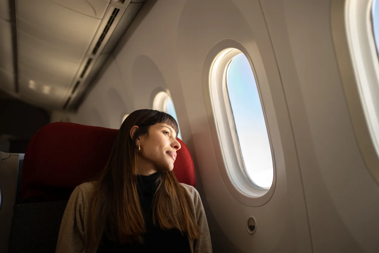 Young woman on a plane looking out the window